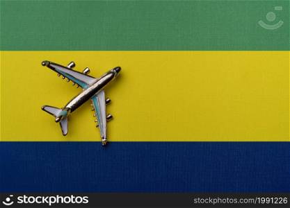 Plane over the flag of Gabon, the concept of travel. Toy plane on the flag as a background.. Plane over the flag of Gabon, the concept of travel.