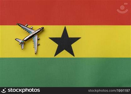 Plane over the flag of Ghana, the concept of journey. Toy plane on the flag as a background.. Plane over the flag of Ghana, the concept of journey.
