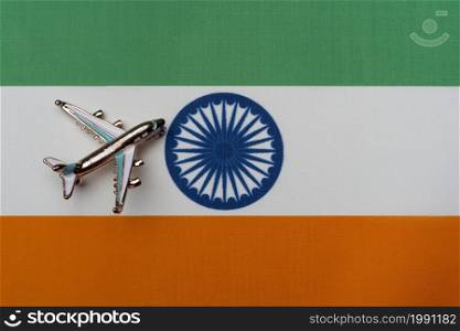 Plane over the flag of India, the concept of journey. Toy plane on the flag as a background.. Plane over the flag of India, the concept of journey.