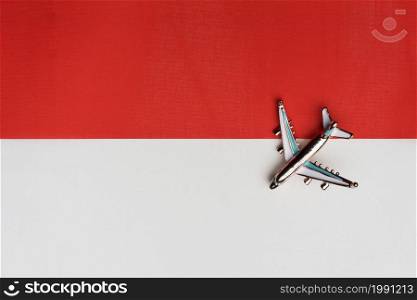 Plane over the flag of Indonesia, the concept of journey. Toy plane on the flag as a background.. Plane over the flag of Indonesia, the concept of journey.