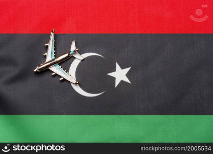 Plane over the flag of Libya island travel and tourism concept. Toy plane on a flag in the background.. Plane over the flag of Libya island travel and tourism concept.