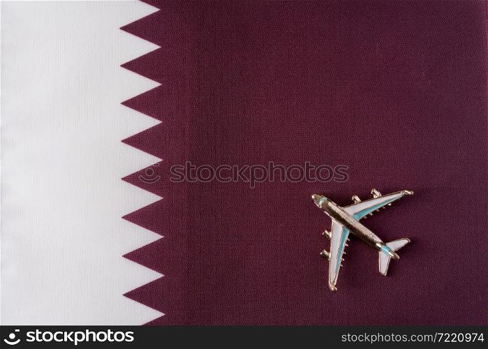 Plane over the flag of Qatar travel concept. Toy plane on a flag in the background.. Plane over the flag of Qatar travel concept.