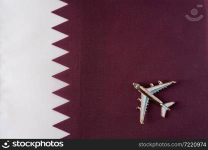 Plane over the flag of Qatar travel concept. Toy plane on a flag in the background.. Plane over the flag of Qatar travel concept.