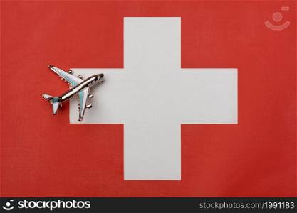 Plane over the flag of Switzerland, the concept of journey. Toy plane on the flag as a background.. Plane over the flag of Switzerland, the concept of journey.