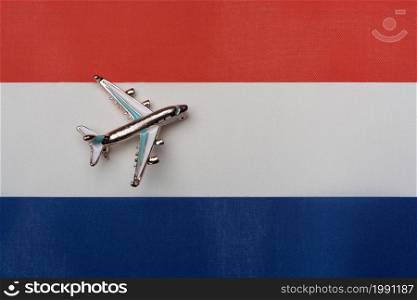 Plane over the flag of the Netherlands, the concept of journey. Toy plane on the flag as a background.. Plane over the flag of the Netherlands, the concept of journey.