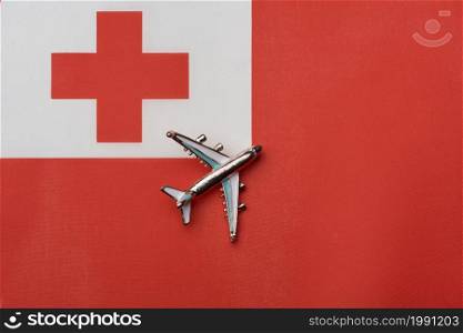 Plane over the flag of Tonga, the concept of journey. Toy plane on the flag as a background.. Plane over the flag of Tonga, the concept of journey.