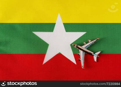 Plane over the flag to Myanmar travel concept. Toy plane on a flag in the background.. Plane over the flag to Myanmar travel concept.