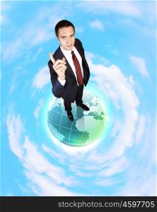 Planet earth against sky background and businessman standing on top of it