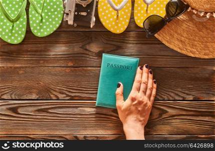 Planning a beach trip. Woman&rsquo;s hands over passport. Travel items for beach tourism still life over wooden background.