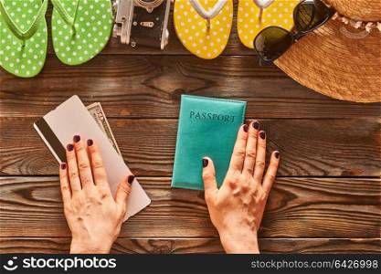 Planning a beach trip. Woman&rsquo;s hands over passport and boarding pass. Travel items for beach tourism still life over wooden background.