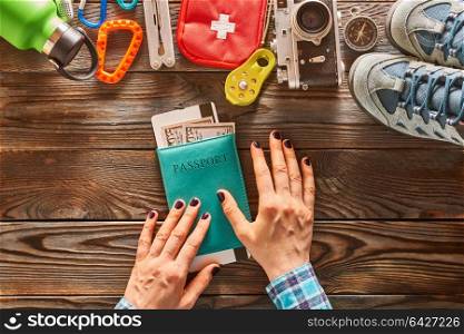 Planning a trip. Woman&rsquo;s hands over passport. Travel items for hiking tourism still life over wooden background