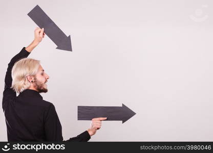 Planning, directions, choices concept. Man holding two black arrows pointing right. Indoor shot on light background. Man holding two arrows pointing same direction