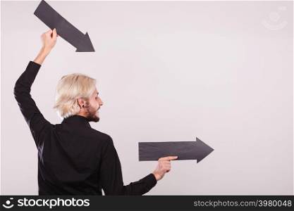Planning, directions, choices concept. Man holding two black arrows pointing right. Indoor shot on light background. Man holding two arrows pointing same direction