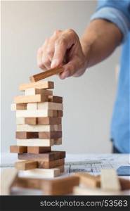 Planning, risk and strategy in business, businessman and engineer gambling placing wooden block on a tower
