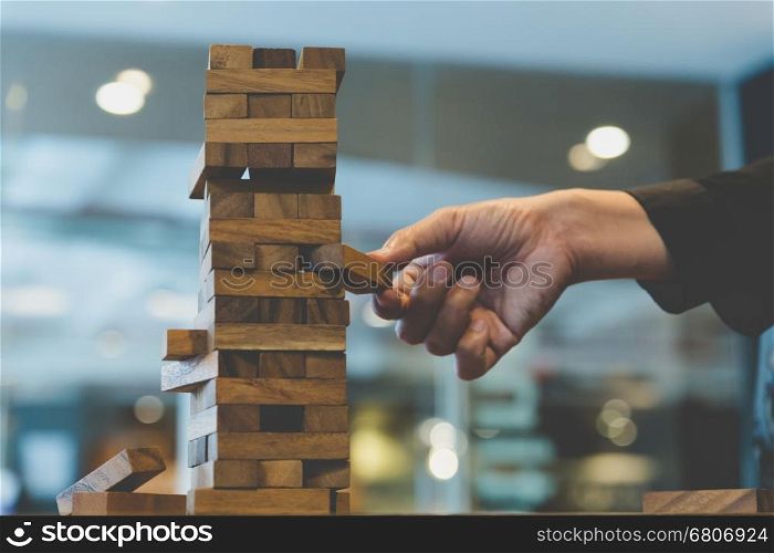 planning, risk and strategy in business, businessman gambling placing wooden block on a tower - blur for background