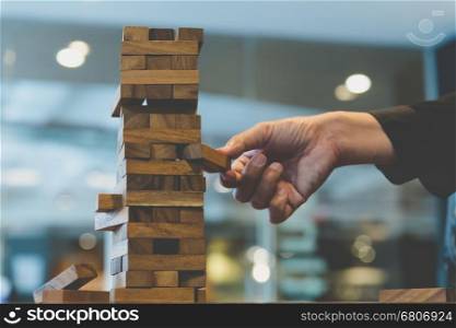 planning, risk and strategy in business, businessman gambling placing wooden block on a tower - blur for background