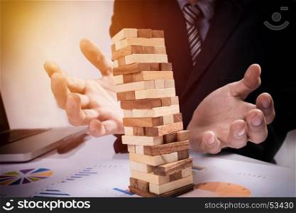 Planning, risk and strategy in business concept, businessman gambling placing wooden block on a tower.