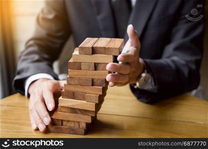 Planning, risk and wealth strategy in business concept, businessman and insurance gambling placing wooden block on a tower.