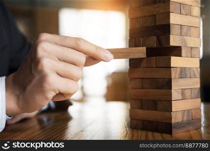 Planning, risk and wealth strategy in business concept, businessman and insurance gambling placing wooden block on a tower.