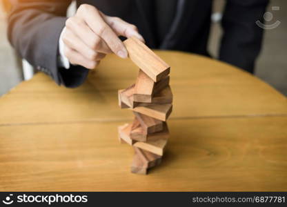 Planning, risk and wealth strategy in business concept, businessman and insurance gambling placing wooden block on a tower.