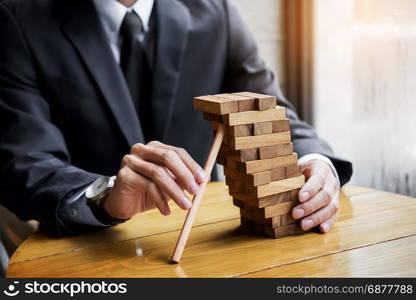 Planning, risk and wealth strategy in business concept, businessman and insurance gambling placing wooden block on a tower.