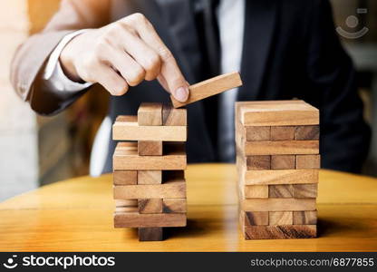 Planning, risk and wealth strategy in business concept, businessman and insurance gambling placing wooden block on a tower.