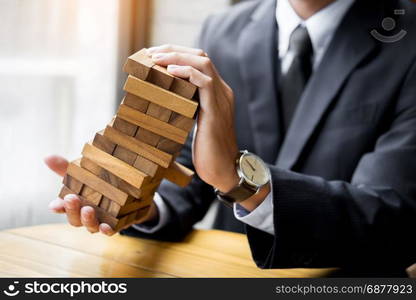 Planning, risk and wealth strategy in business concept, businessman and insurance gambling placing wooden block on a tower.