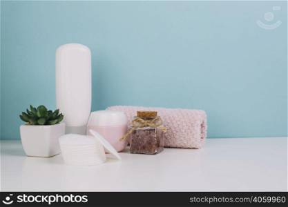 plant cosmetics bottles near towel cotton pads
