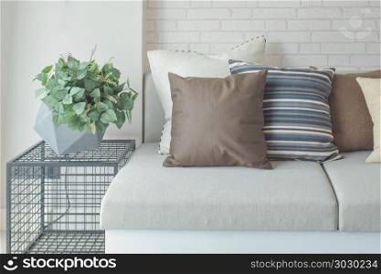 Plant pot on side table next to beige color sofa
