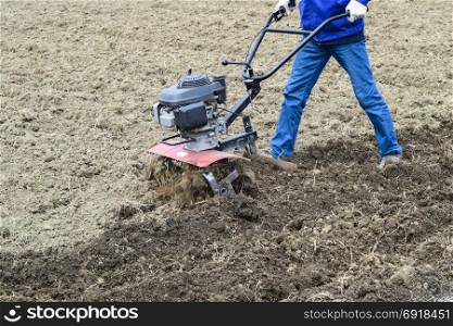 Planting potatoes under the walk-behind tractor. Man with motor-block in the garden.. Planting potatoes under the walk-behind tractor