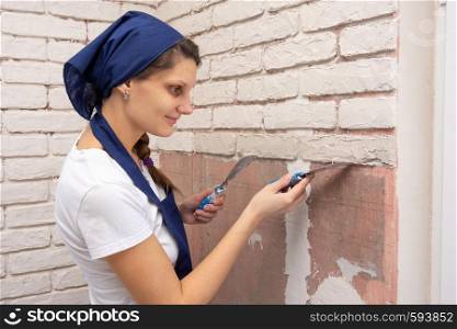 Plasterer girl forms from a plaster mass bricks on the wall
