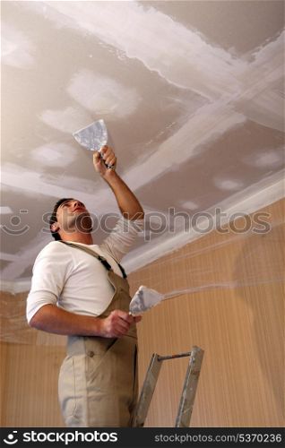 Plasterer working on ceiling