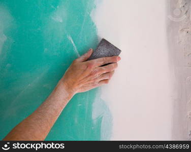 plastering man hand sanding the plaste in drywall seam plasterboard