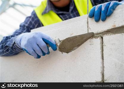 Plastering the wall.Hand holding a spatula with construction mix.Applying putty or tile glue to with lightweight concrete blocks.Plaster the wall with a putty knife.Internal construction,Construction concept.