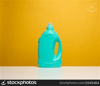 plastic blue bottle with liquid detergent stand on a white table, yellow background