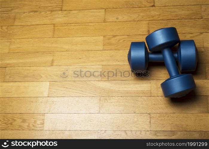 Plastic blue dumbbells on wooden, brown floor. The concept of a healthy lifestyle, fitness.. Plastic blue dumbbells on wooden, brown floor.