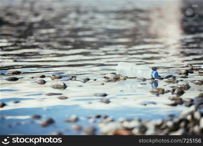 Plastic bottle is lying on the stony beach, environmental pollution