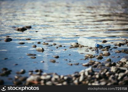Plastic bottle is lying on the stony beach, environmental pollution