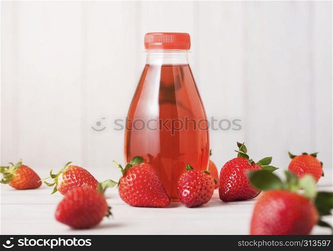 Plastic bottle of berries soda juice drink on wooden background with fresh strawberries