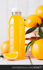 Plastic bottle of organic fresh orange juice with raw oranges in white wooden box