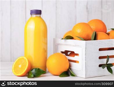 Plastic bottle of organic fresh orange smoothie juice with raw oranges in white wooden box
