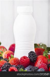 Plastic bottle with fresh summer berries smoothie on wooden background.Strwberries and raspberies with blueberries and blackberries.