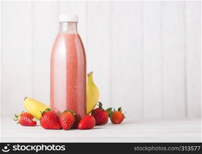 Plastic bottle with fresh summer berries smoothie on wooden background.Strwberry and banana flavour.