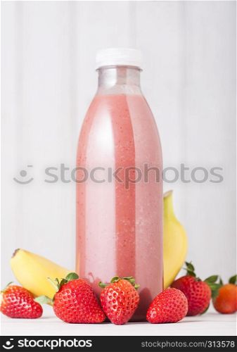 Plastic bottle with fresh summer berries smoothie on wooden background.Strwberry and banana flavour.