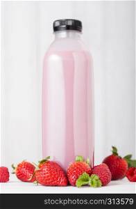 Plastic bottle with fresh summer berries smoothie on wooden background.Strwberry flavour.