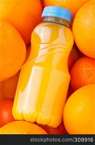 Plastic bottles of organic fresh orange juice with raw oranges background