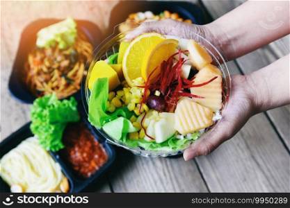 Plastic box food delivery in take away boxes package on table at home, Healthy food box in hand with fruit lettuce vegetable salad sauce service food order online delivery