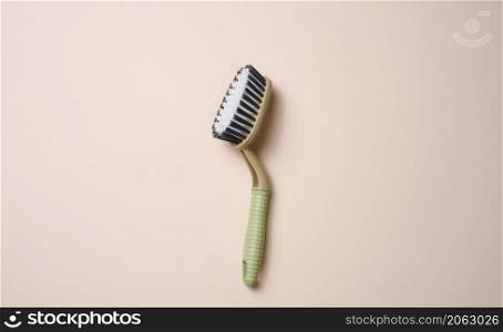 plastic brush with handle for cleaning the house on beige background, top view
