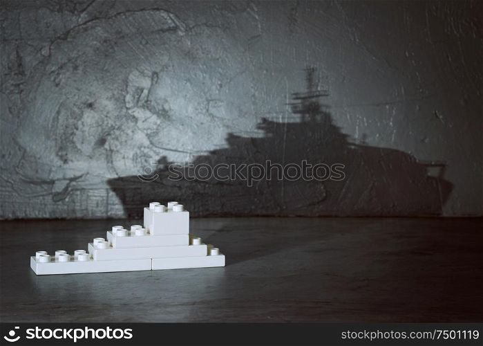 Plastic building blocks with ship shadow . Creative and ideal concept . Concrete interior background .