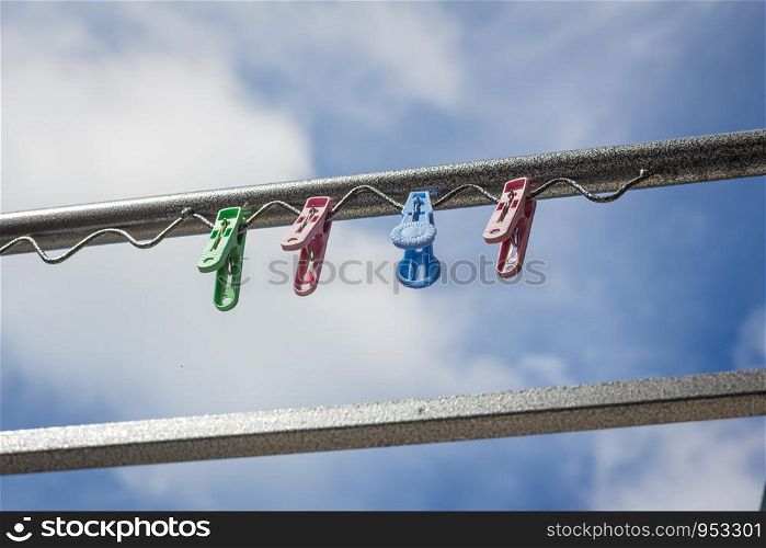 Plastic clothespin on a clothesline and in the daytime sky.